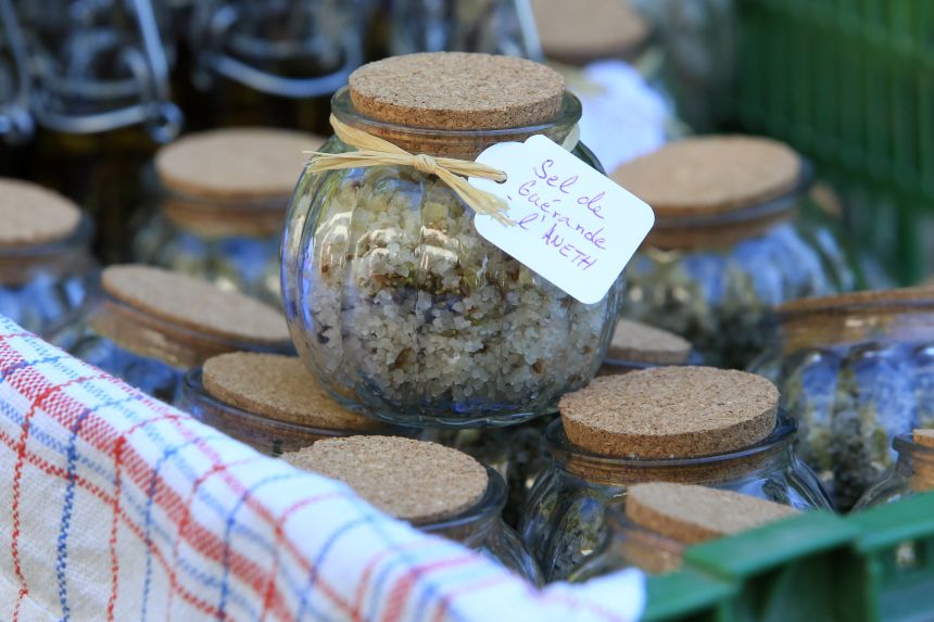 Keltská sůl ve skleněné nádobce s dřevěným víčkem někde na tržišti, položená na jiných nádobkách.